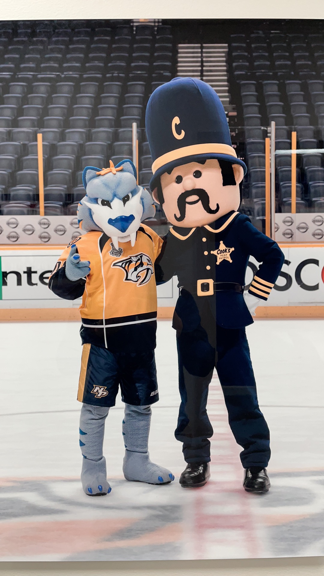 The Cook's mascot with the Nashville Predators mascot on the ice at Bridgestone Arena